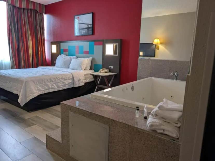 a hotel room with a bed and a bath tub at Ramada by Wyndham East Orange in East Orange