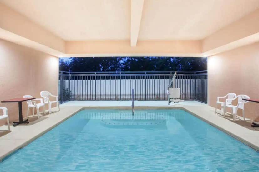 a swimming pool with two chairs and a table at Ramada by Wyndham Fresno Northwest in Fresno