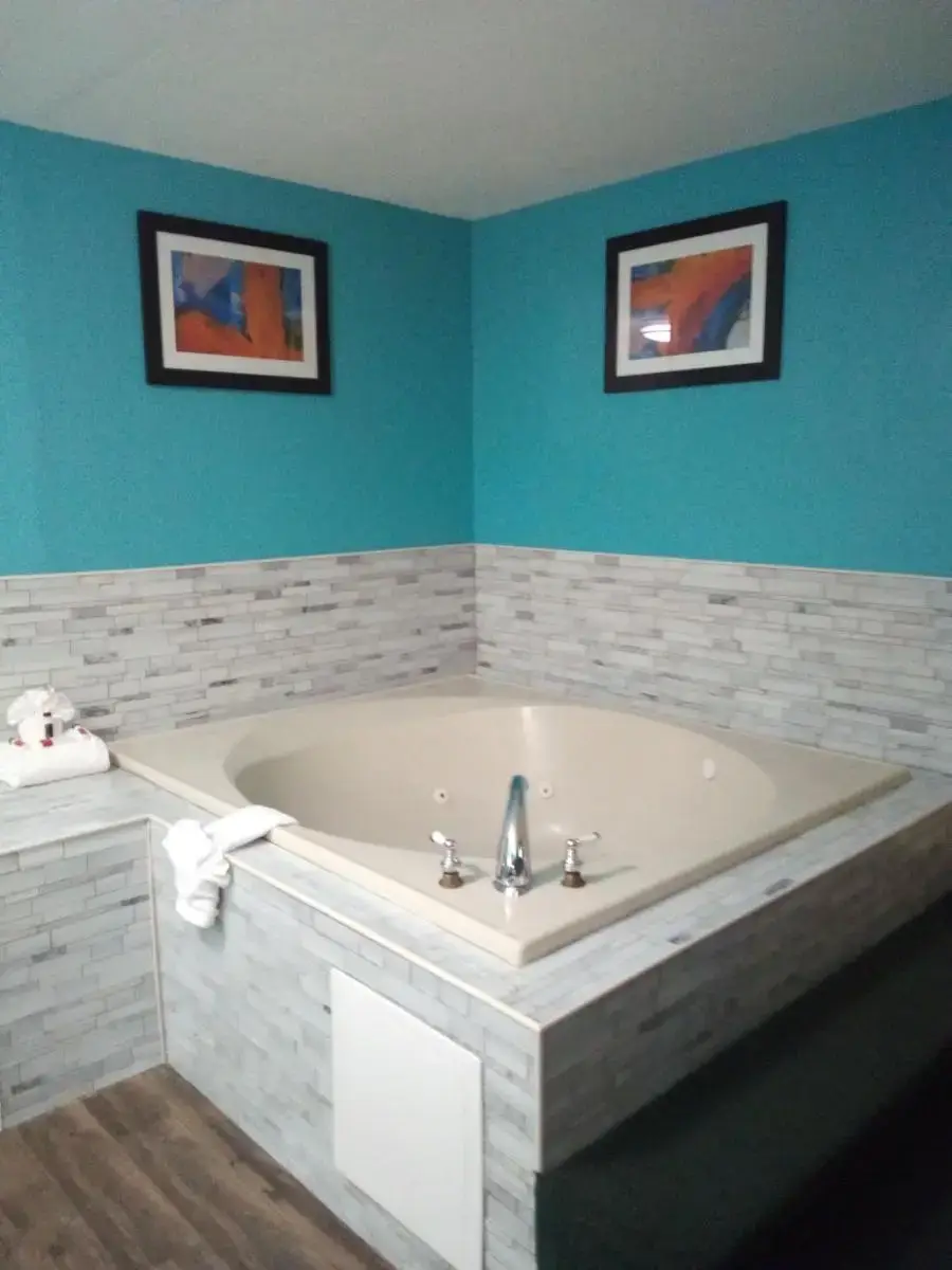a large bath tub in a bathroom with blue walls at Ramada by Wyndham Groton Mystic in Groton