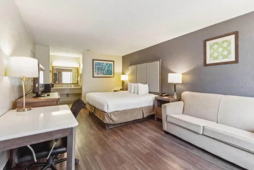 a hotel room with a bed and a couch at Ramada by Wyndham Houma in Houma