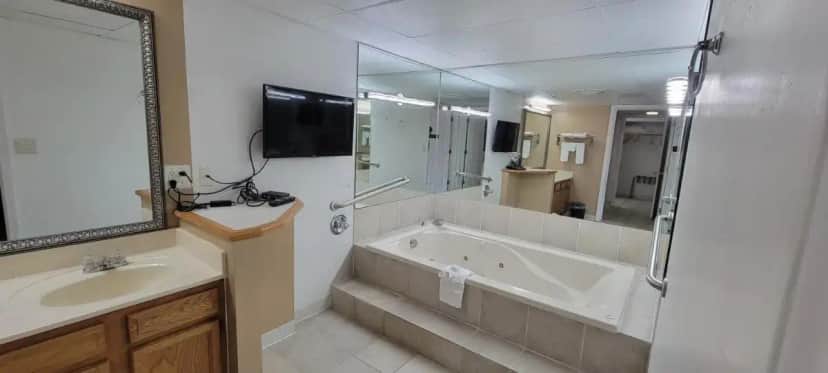 a bathroom with a tub and a sink and a mirror at Ramada by Wyndham Mountain Home in Mountain Home