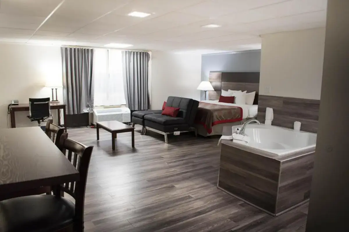 a hotel room with a bed and a couch and a tub at Ramada by Wyndham North Platte in North Platte
