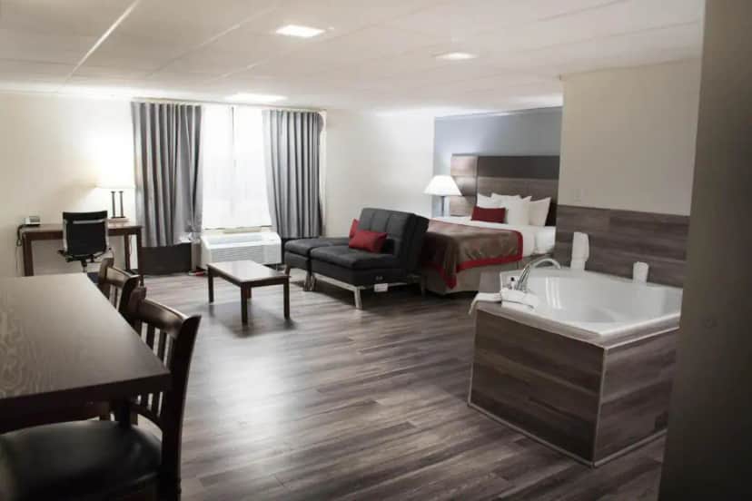 a hotel room with a bed and a couch and a tub at Ramada by Wyndham North Platte in North Platte
