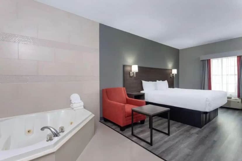 a hotel room with a bed and a bath tub at Ramada by Wyndham Sellersburg/Louisville North in Sellersburg