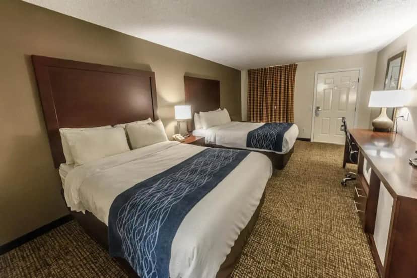 a hotel room with two beds and a desk at Richland Inn in Lawrenceburg