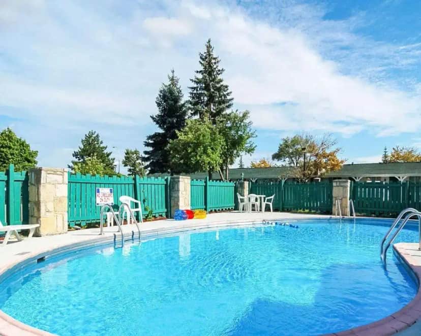 a large swimming pool with chairs and a fence at Rodeway Inn Madison Heights - Detroit in Madison Heights