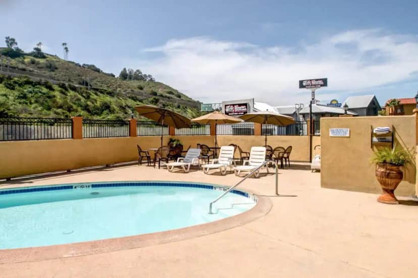 a swimming pool with chairs and tables and umbrellas at Rodeway Inn San Diego Near SDSU in San Diego