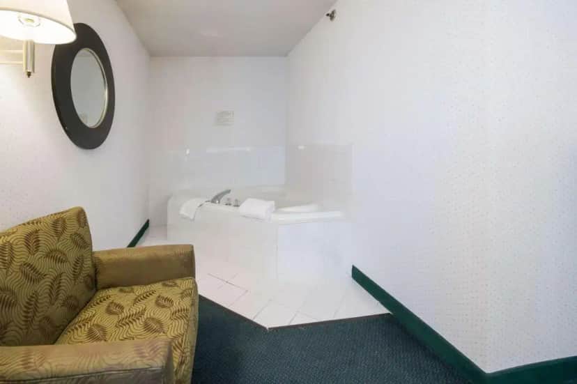 a living room with a chair and a tub at Rodeway Inn Urbana Champaign University Area in Champaign