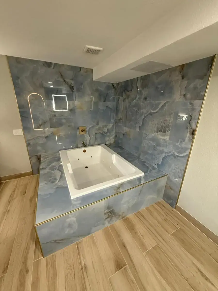 a bath tub in a room with a stone wall at Rosemead Motel in Rosemead