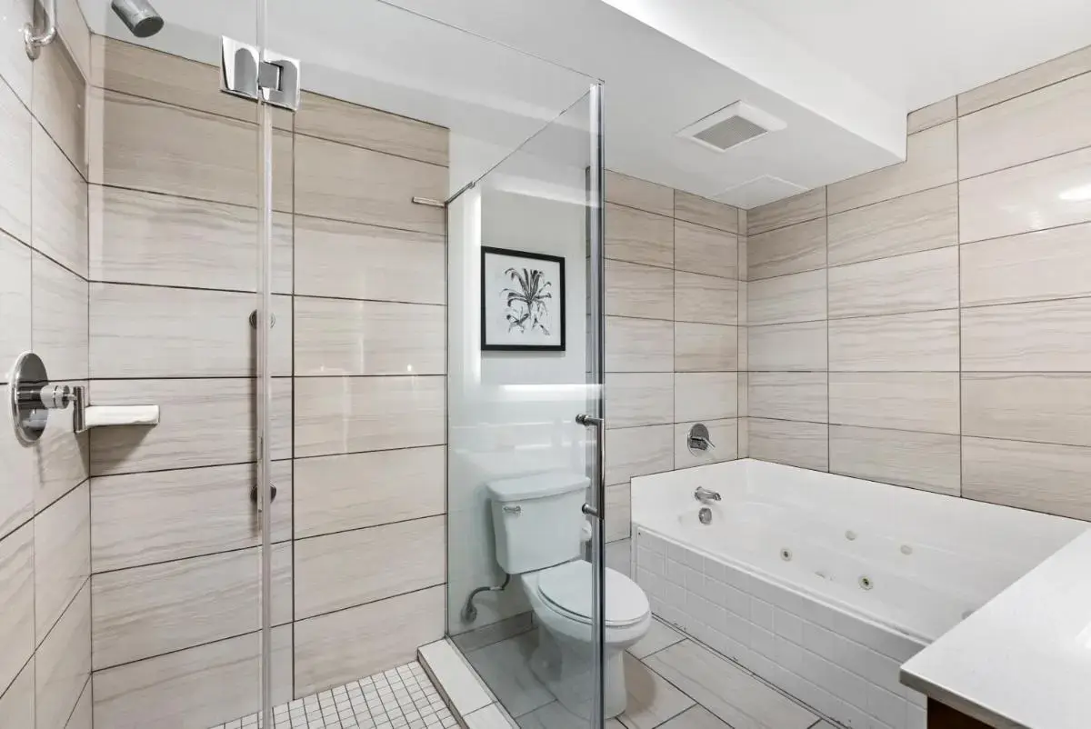 a bathroom with a tub and a toilet and a sink at Royal Palace Westwood Hotel in Los Angeles