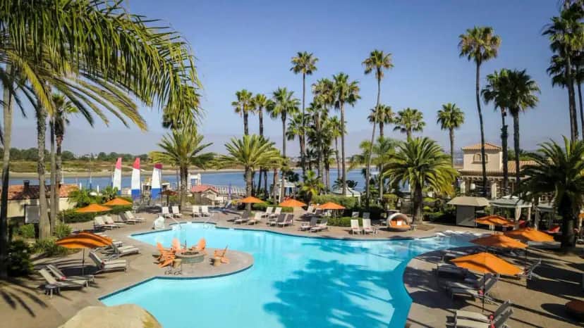 a large pool with chairs and umbrellas and palm trees at San Diego Mission Bay Resort in San Diego