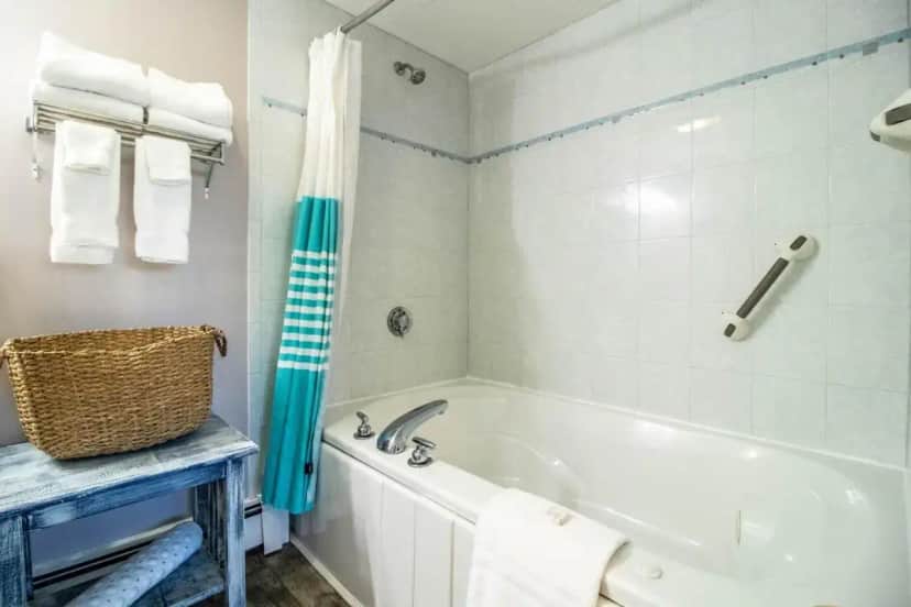 a bathroom with a white tub and a blue shower curtain at Sea View Motel in Ogunquit