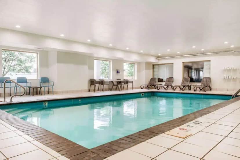 a pool in a hotel with chairs and tables at Sleep Inn & Suites Columbus South in Columbus