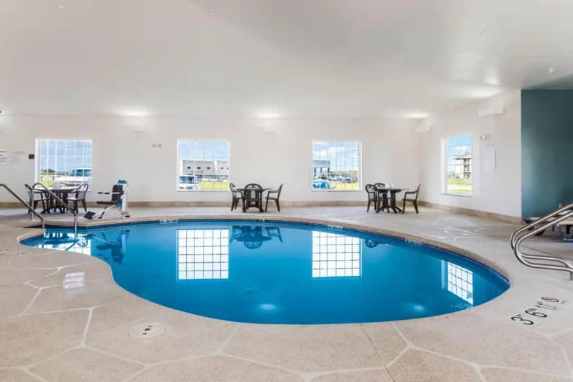 a pool in a room with tables and chairs at Sleep Inn & Suites North Liberty - Liberty City in North Liberty