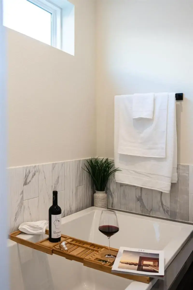 a bathroom with a bath tub and a bottle of wine at Sleeps 40! 4 Luxe Homes Together Rice Military in Houston