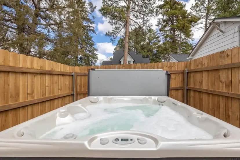 a hot tub in a backyard with a wooden fence at Spearfish Cottages in Spearfish
