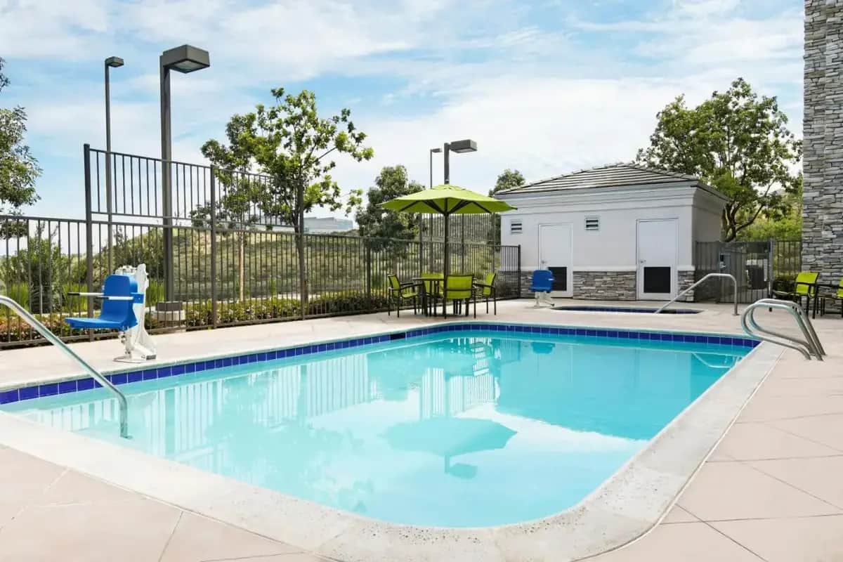 a swimming pool with chairs and an umbrella at SpringHill Suites by Marriott San Diego Rancho Bernardo-Scripps Poway in Poway