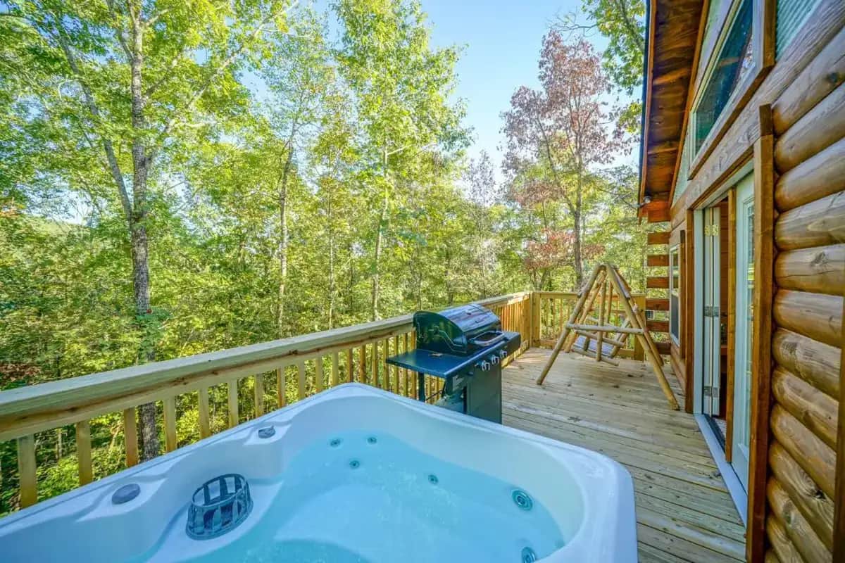 a jacuzzi tub on the deck of a cabin at Starlight Haven Hot Springs in Hot Springs