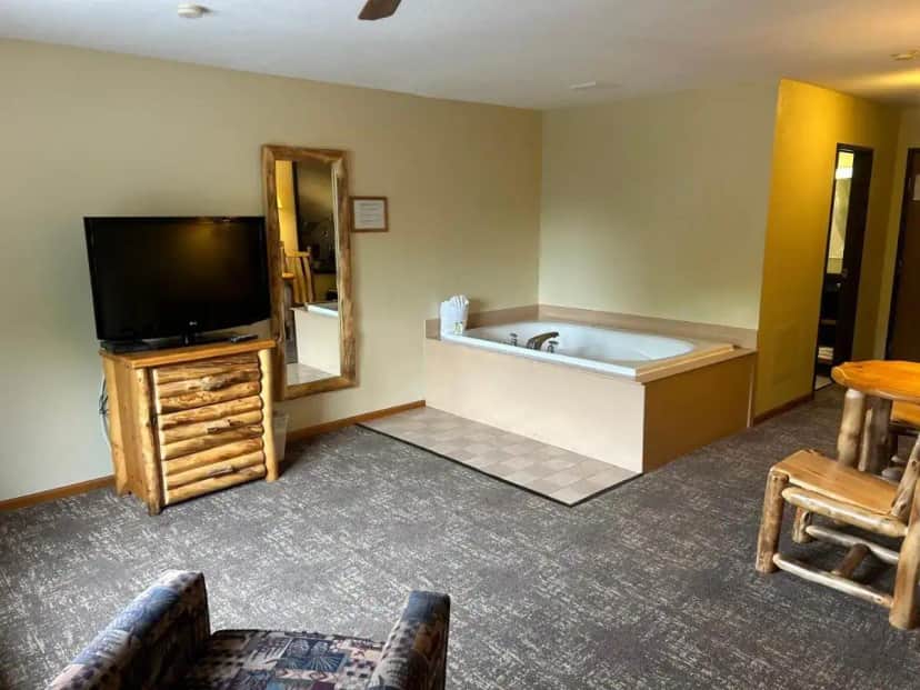 a room with a tub and a tv and a television at Super 8 by Wyndham Bridgeview of Mackinaw City in Mackinaw City