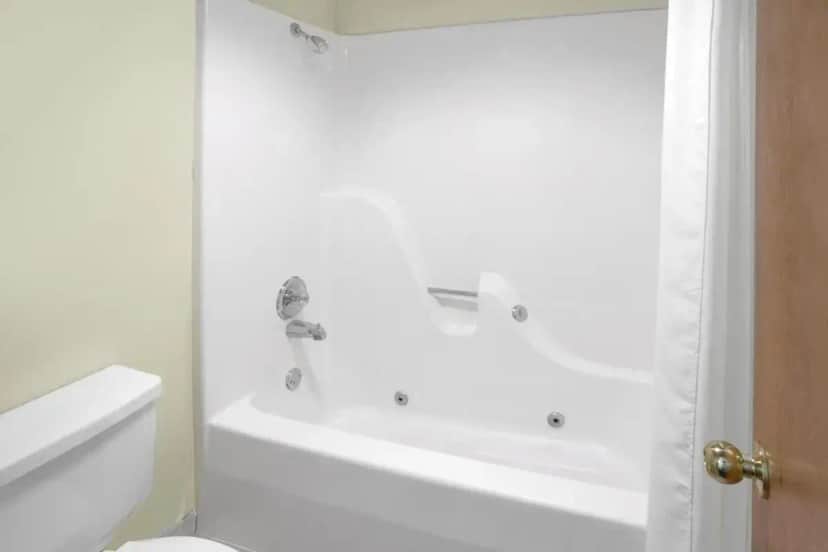 a white bathroom with a tub and a toilet at Super 8 by Wyndham Clarksville AR in Clarksville