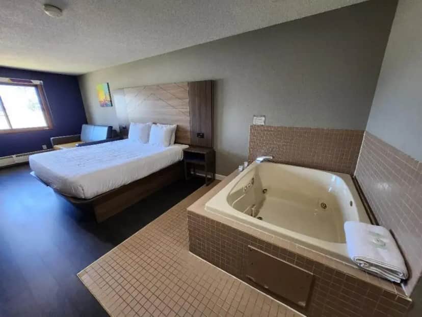 a hotel room with a bed and a bath tub at Super 8 by Wyndham Hayward WI in Hayward