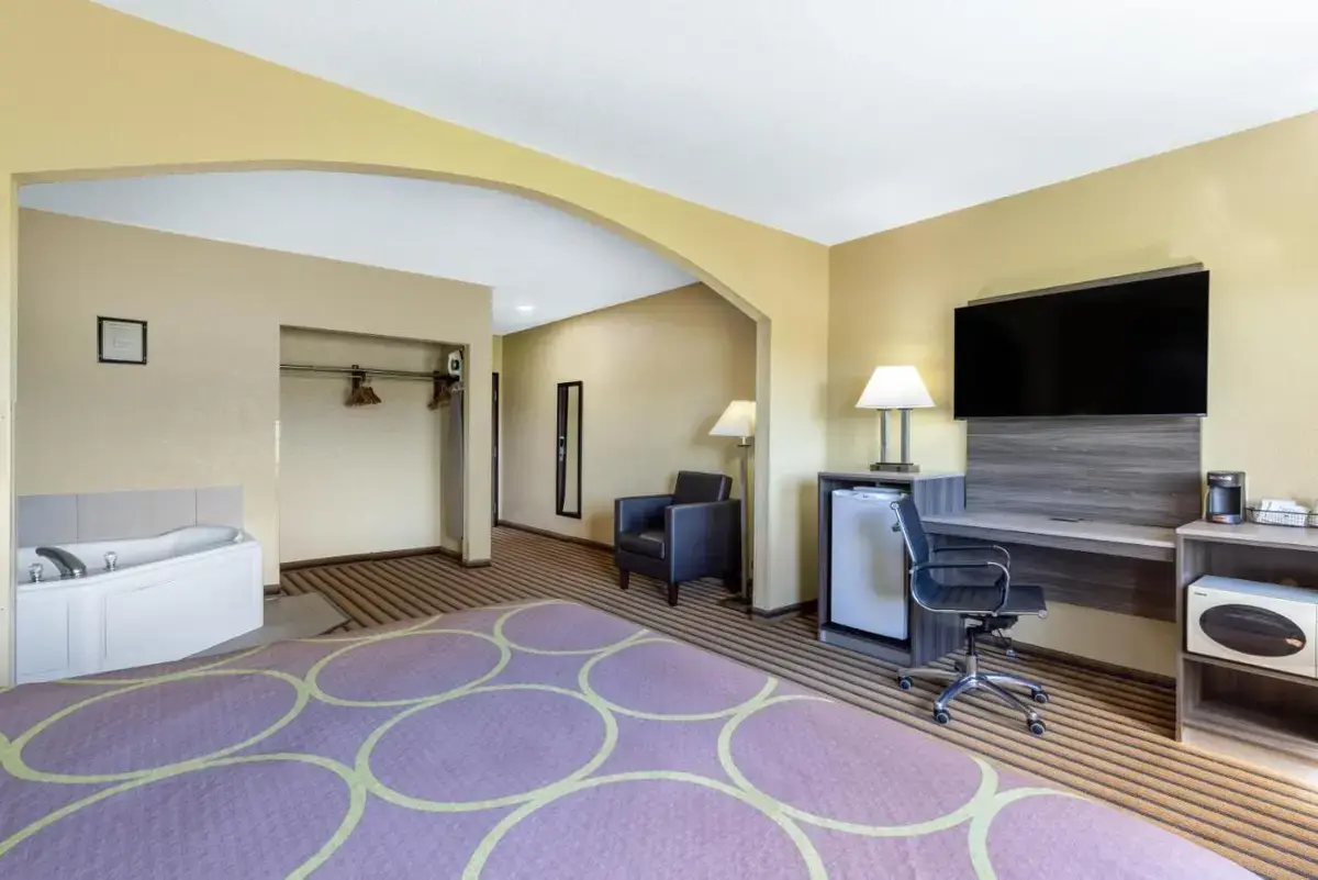 a hotel room with a bed and a desk and a flat screen tv at Super 8 by Wyndham Nixa/Springfield Area in Nixa