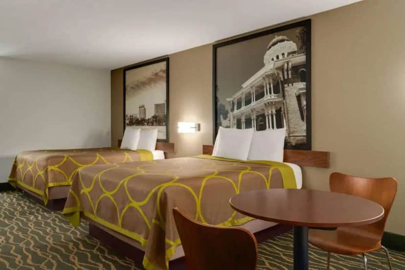 a hotel room with two beds and a table at Super 8 by Wyndham Pearl/Jackson Airport in Pearl