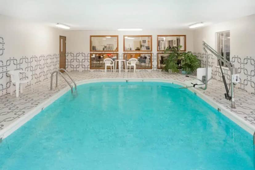 a large swimming pool with blue water in a building at Super 8 by Wyndham Pekin/Peoria Area in Pekin