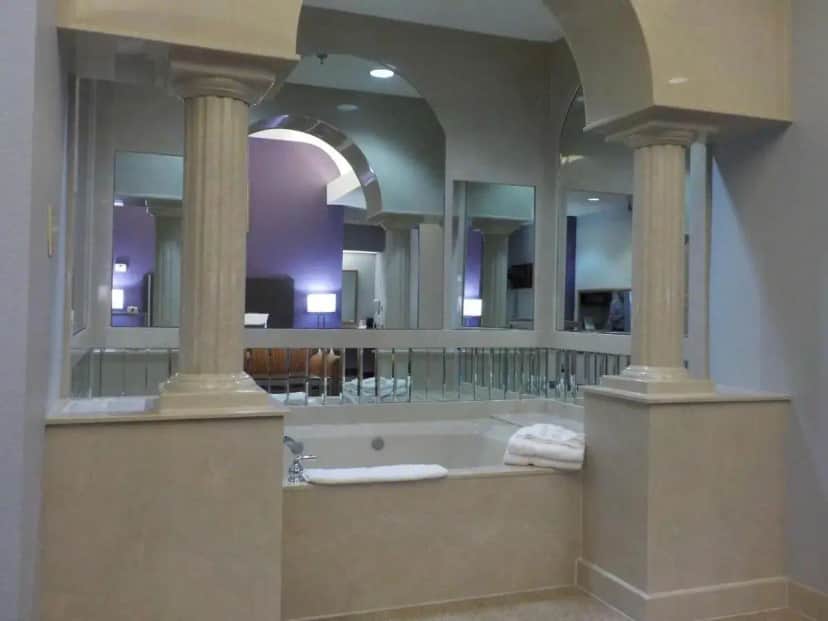 a bathroom with a tub with a large mirror at SureStay Plus Hotel by Best Western Warner Robins AFB in Warner Robins