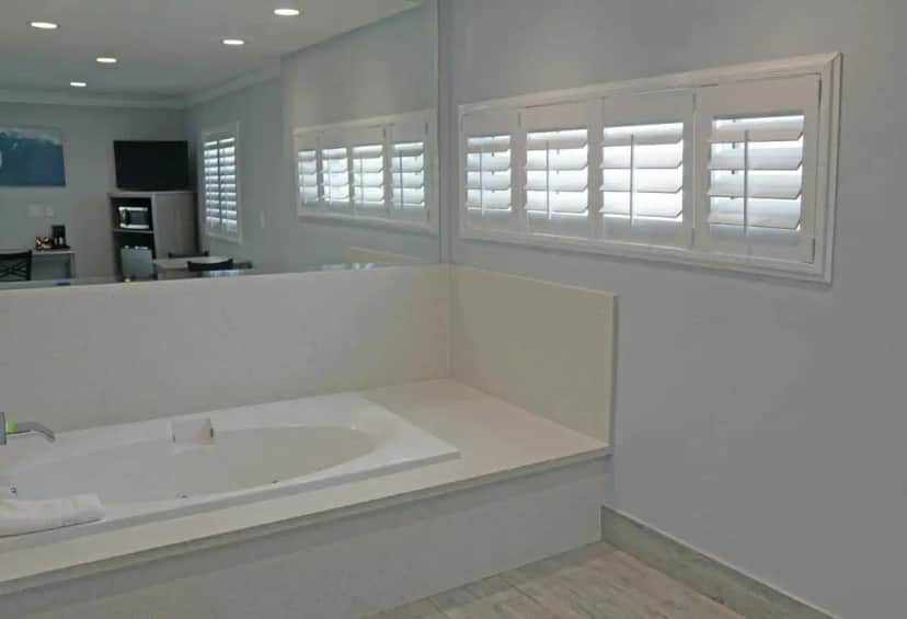 a white bathroom with a large tub and windows at Surf City Inn in Huntington Beach