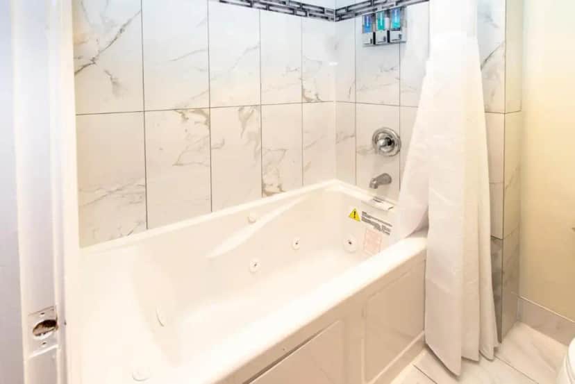 a white bathroom with a tub and a shower at Surf Motel and Gardens in Fort Bragg
