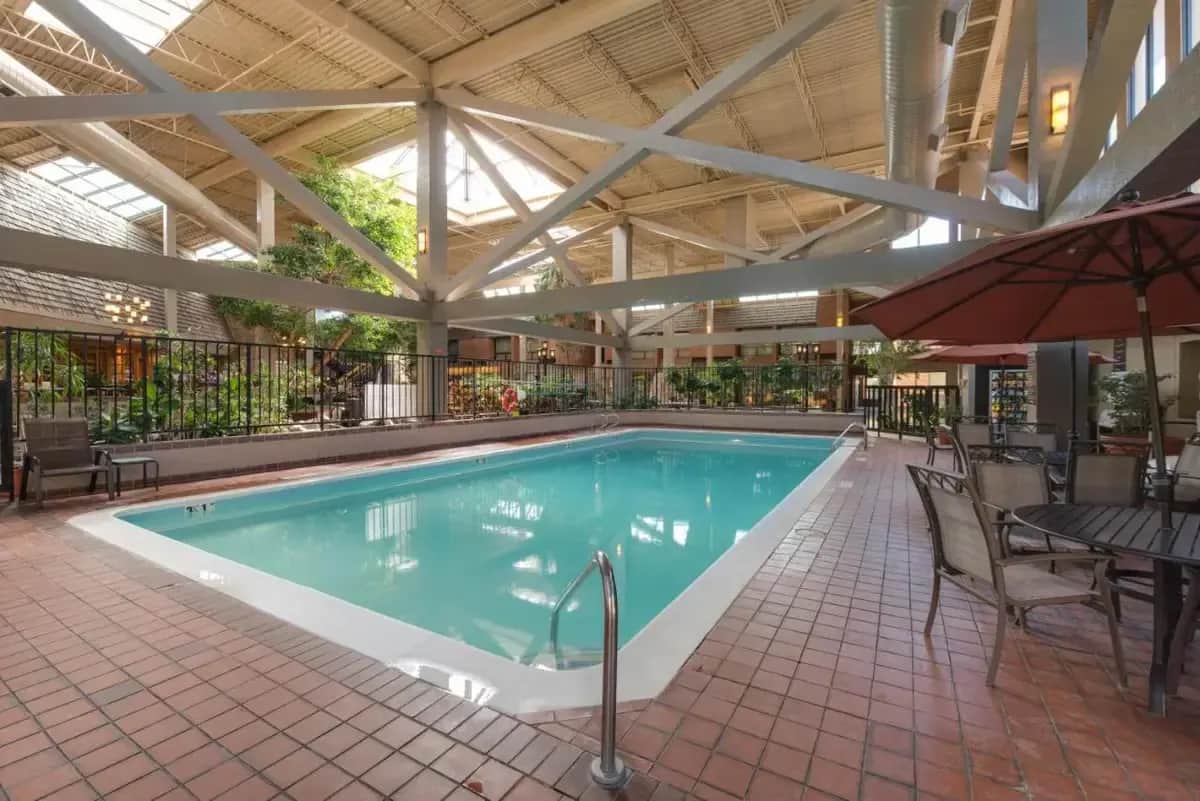a swimming pool with a table and chairs and an umbrella at The Academy Hotel Colorado Springs in Colorado Springs