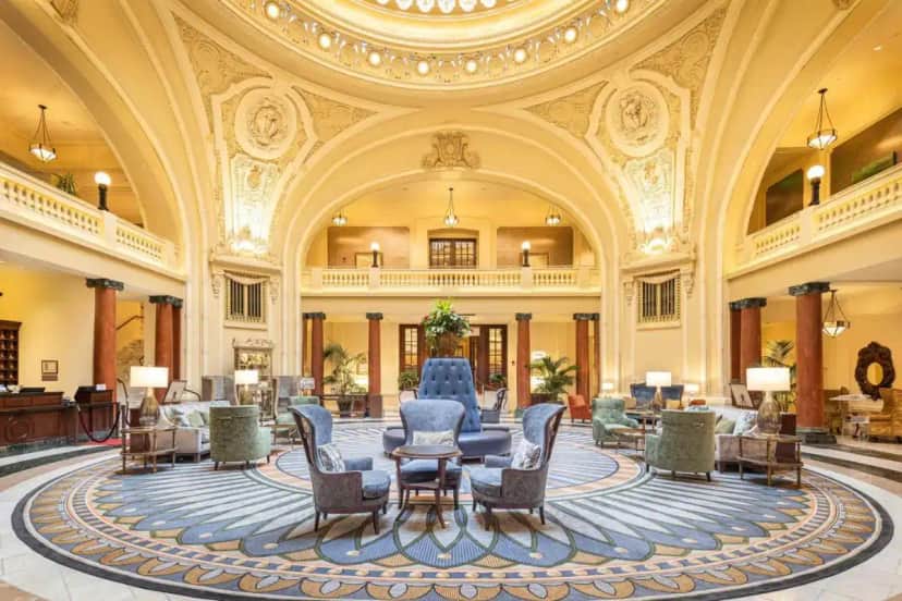 a lobby with chairs and tables in a building at The Battle House Renaissance Mobile Hotel & Spa in Mobile