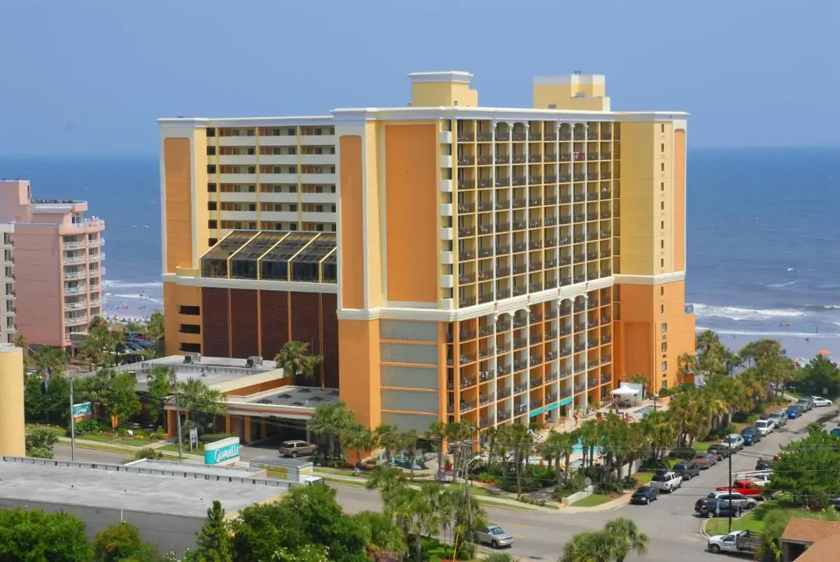 a large yellow building next to the ocean at The Caravelle Resort in Myrtle Beach