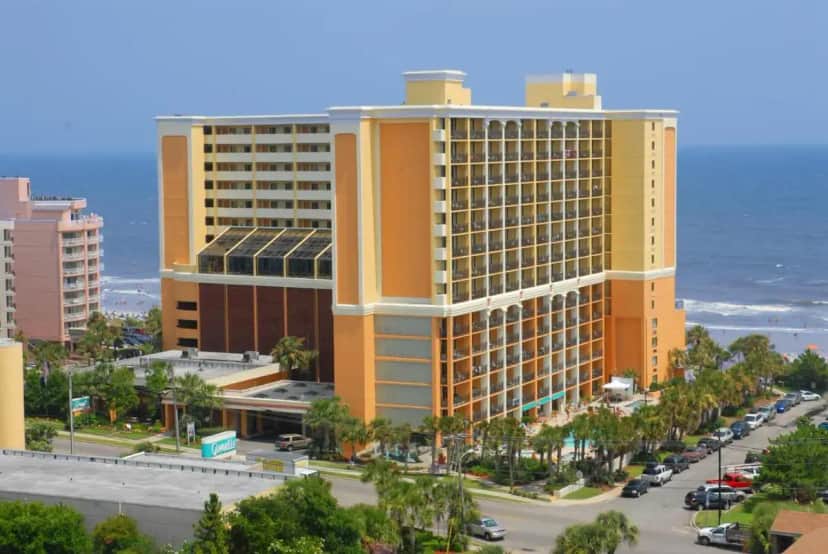 a large yellow building next to the ocean at The Caravelle Resort in Myrtle Beach