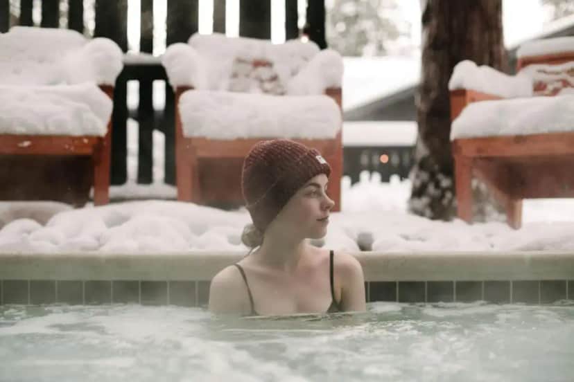 a woman in a hot tub covered in snow at The Coachman Hotel in South Lake Tahoe