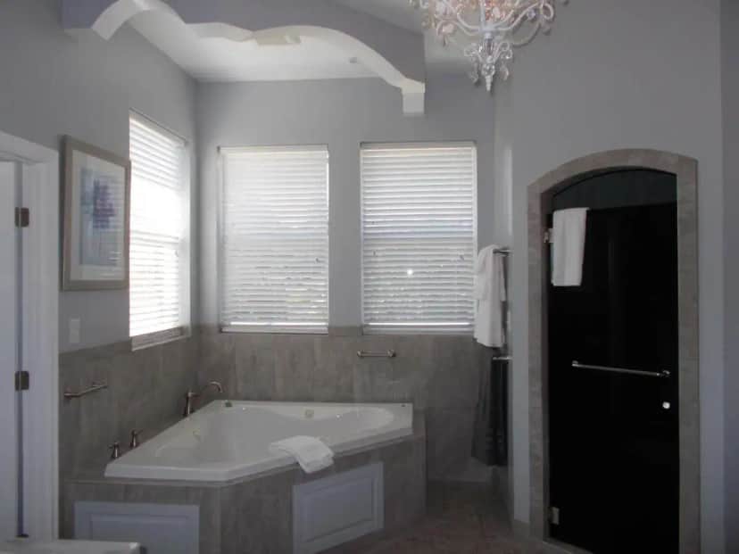 a bathroom with a tub and windows and a chandelier at The Inn at 161 in Sutter Creek
