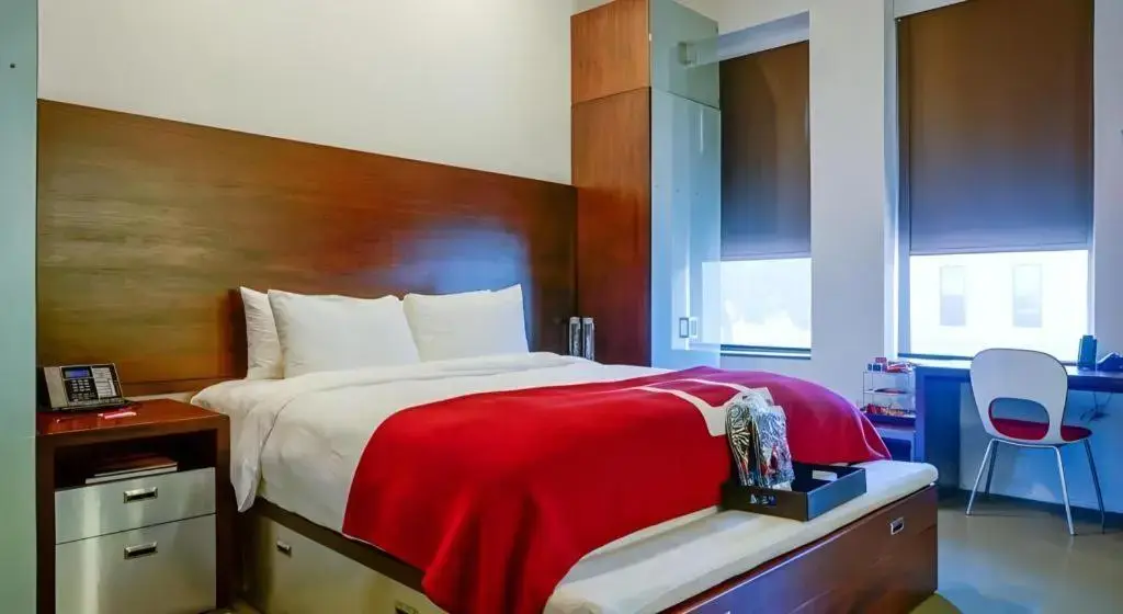 a bedroom with a bed with a red blanket on it at The Keating Hotel by Pininfarina in San Diego