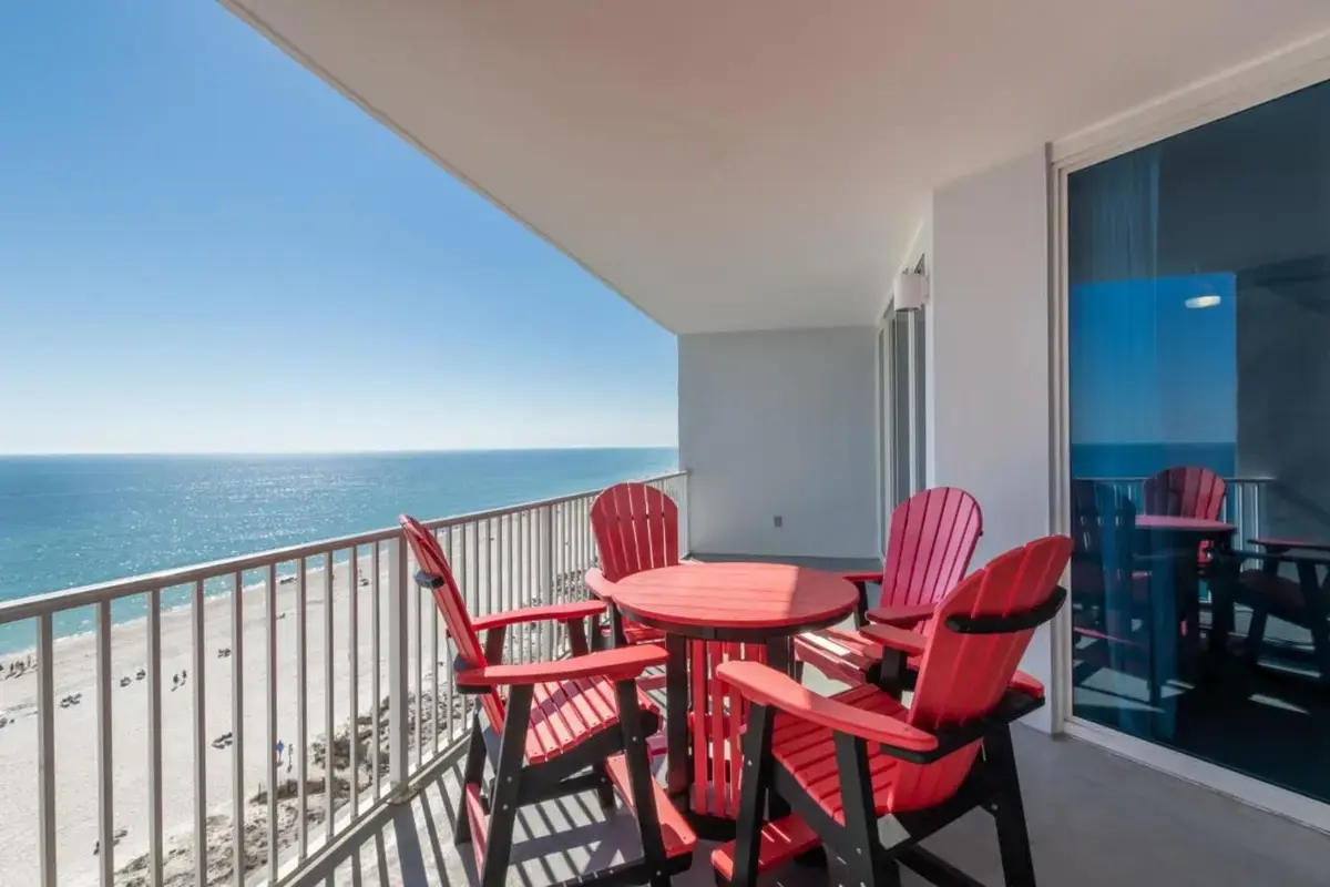 a balcony with a table and chairs and the ocean at Lighthouse Condominiums in Gulf Shores