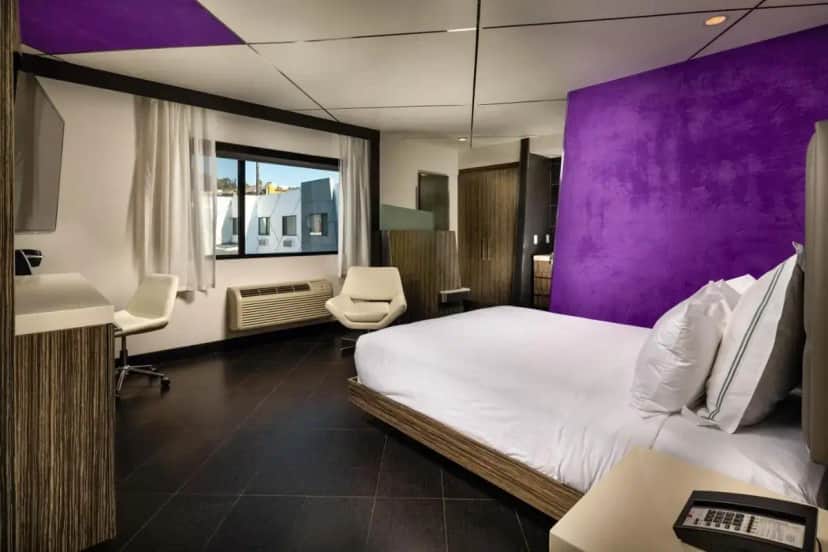 a hotel room with a bed and purple walls at The Moment Hotel in Los Angeles