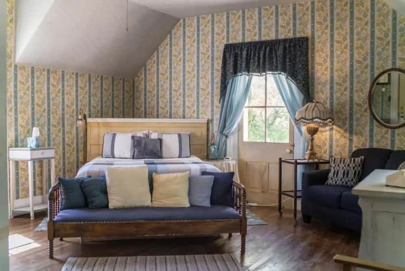 a bedroom with a bed and a couch and a window at The Mulberry Inn -An Historic Bed and Breakfast in St. George