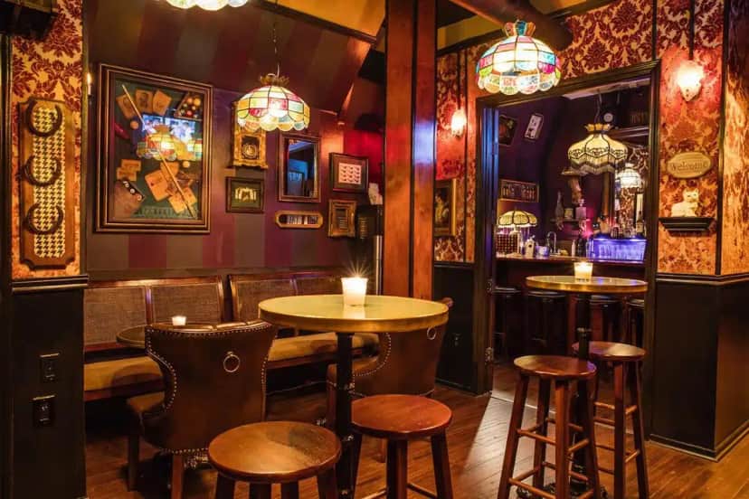 a bar with two tables and stools in a room at The Rosemary in Los Angeles