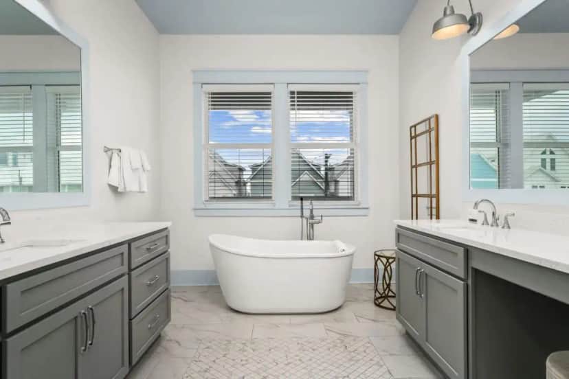 a bathroom with a tub and two sinks and two mirrors at The Surf House 7BR Panama City Beach Rental in Panama City Beach