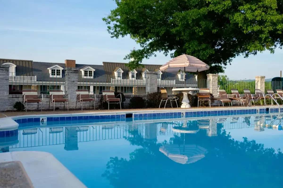 a swimming pool with chairs and an umbrella at The Village Inn in Harrisonburg