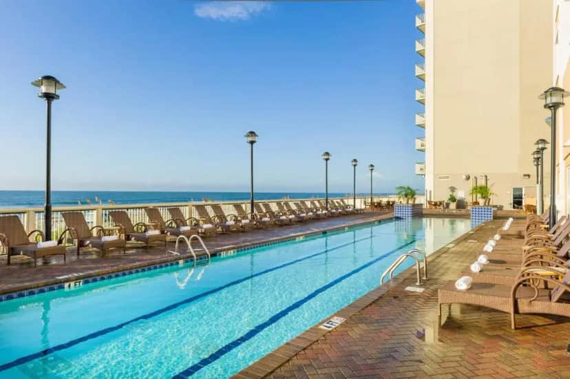 a swimming pool with chairs and the ocean in the background at Westgate Myrtle Beach Oceanfront Resort in Myrtle Beach