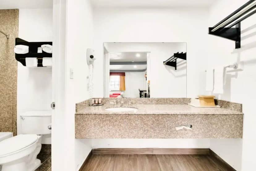 a bathroom with a sink and a toilet and a mirror at Three Rivers Executive Inn & Suites By OYO in Three Rivers