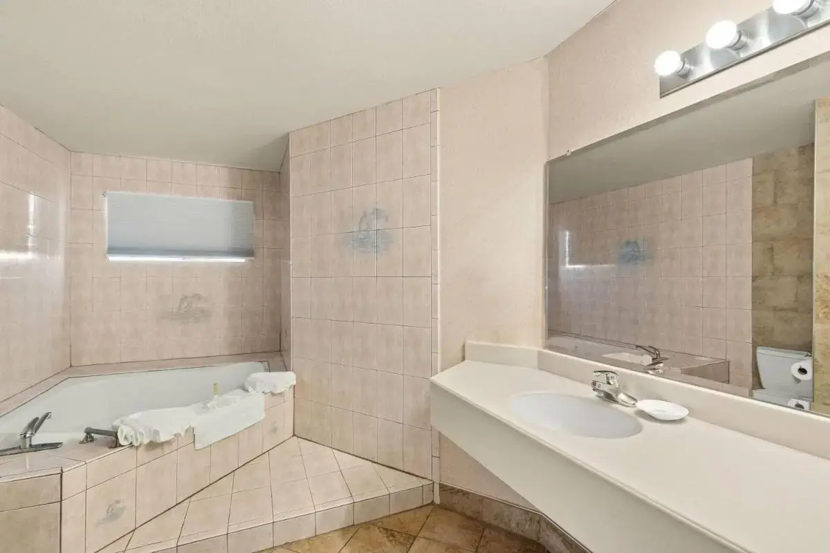 a bathroom with a tub and a sink and a mirror at Travelodge by Wyndham San Clemente Beach in San Clemente