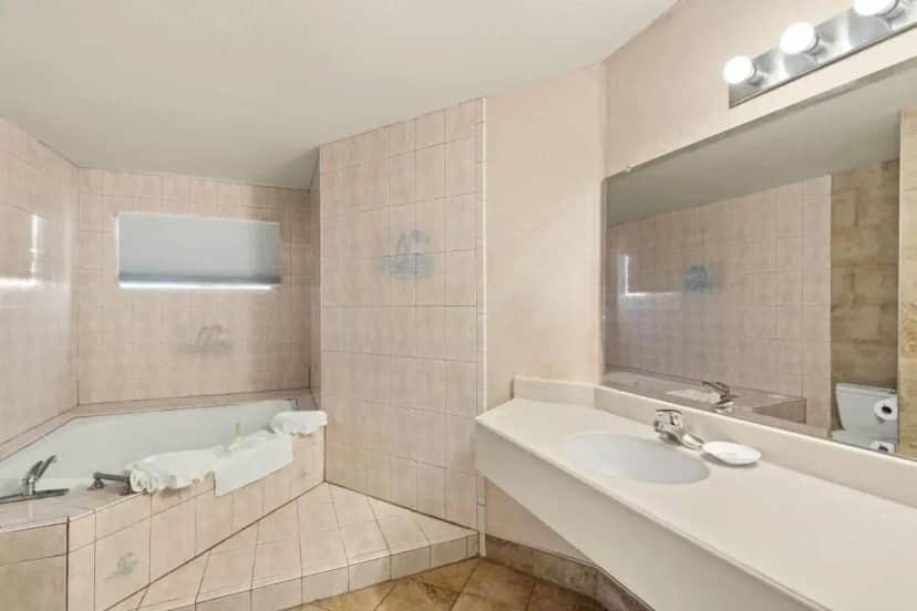 a bathroom with a tub and a sink and a mirror at Travelodge by Wyndham San Clemente Beach in San Clemente