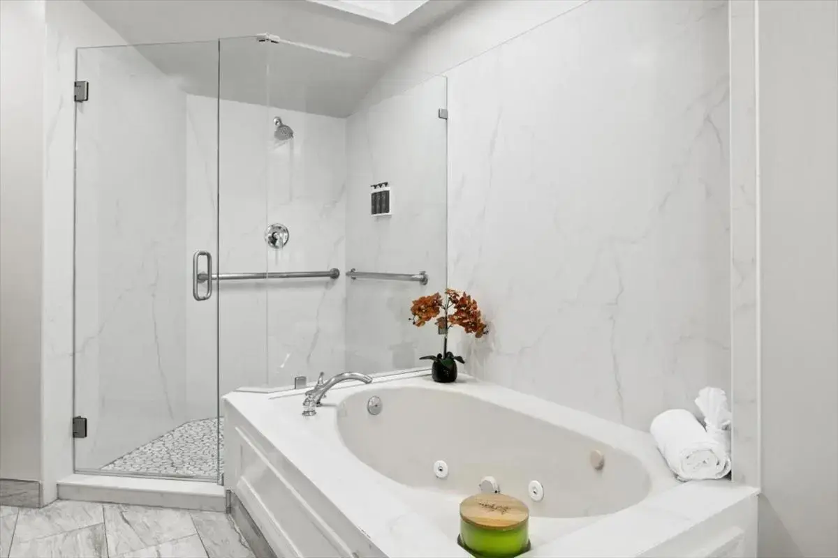 a white bathroom with a tub and a shower at University Park Inn & Suites, an Ascend Collection Hotel in Davis