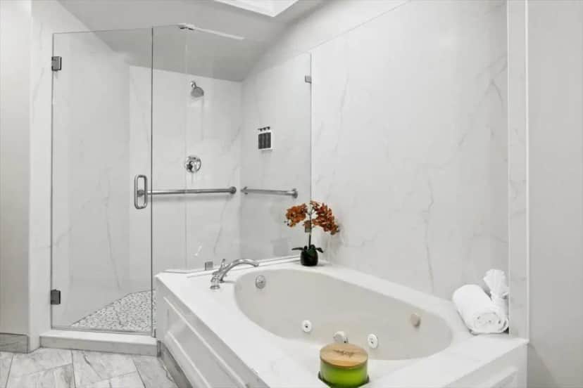 a white bathroom with a tub and a shower at University Park Inn & Suites, an Ascend Collection Hotel in Davis